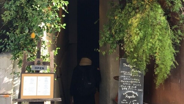 A restaurant entrance with a sign indicating it's open, a chalkboard menu, and a person inside. - North Cottage | Shibuya Studio | Close to Meiji Shrine (Shibuya)