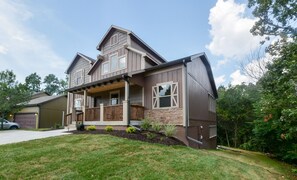 Stunning two-story home with a charming front porch and covered entryway, featuring a combination of siding and stone accents.