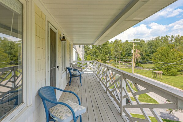 A covered porch with a railing, a window, and a door.