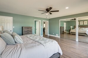 Un dormitorio con cama, ventilador de techo y un espejo grande.