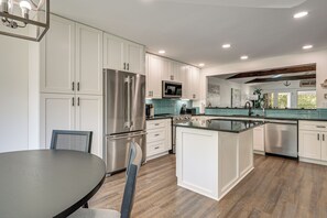 A modern kitchen with white cabinetry, stainless steel appliances, and a central island.