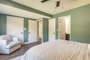 A bedroom with a bed, a chair, and two doors leading to other rooms.