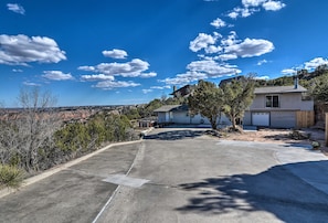 Ein Wohngebiet mit einer Betonauffahrt, einem freistehenden Haus mit Garage und einer hügeligen Landschaft im Hintergrund.
