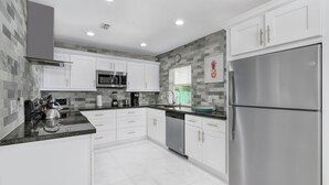 Una cocina moderna con armarios blancos, electrodomésticos de acero inoxidable y un salpicadero de azulejos.