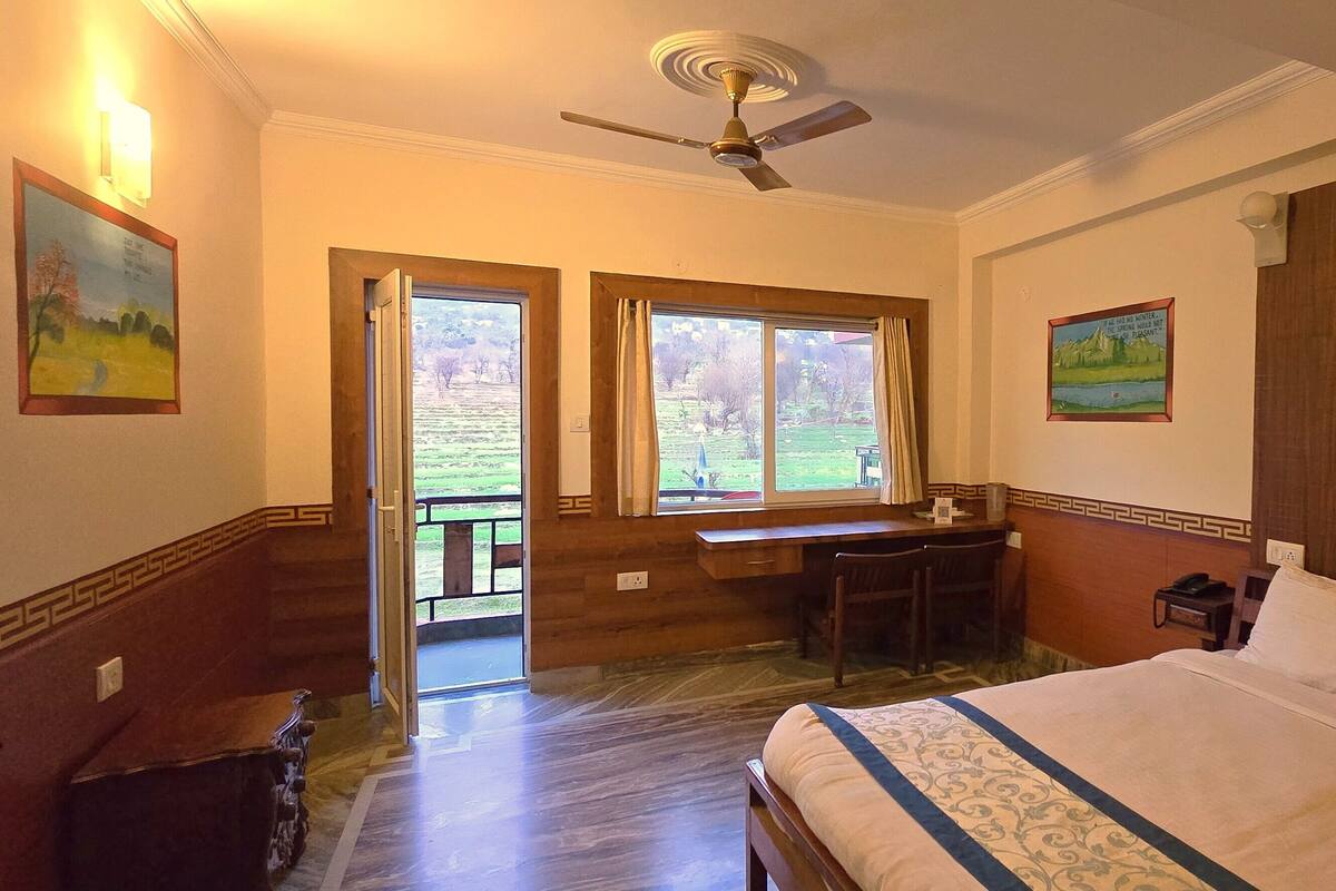 Una habitación de hotel con cama, escritorio y dos ventanas.