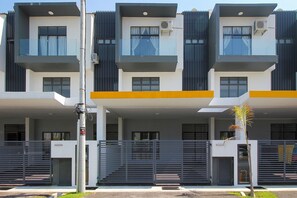 Stylish residential building with a symmetrical facade, featuring balconies and windows with curtains.