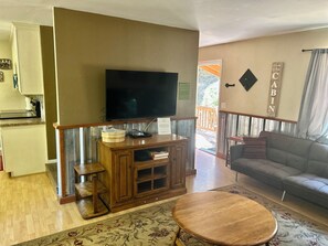 Un salon comprenant un téléviseur, un meuble de rangement en bois, un canapé et une table basse ronde.