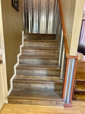 Un escalier en bois avec une rampe en métal, menant à l’étage supérieur.