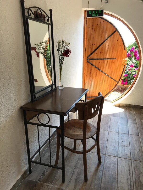 Una mesa de madera con una silla, un espejo y un jarrón con flores.