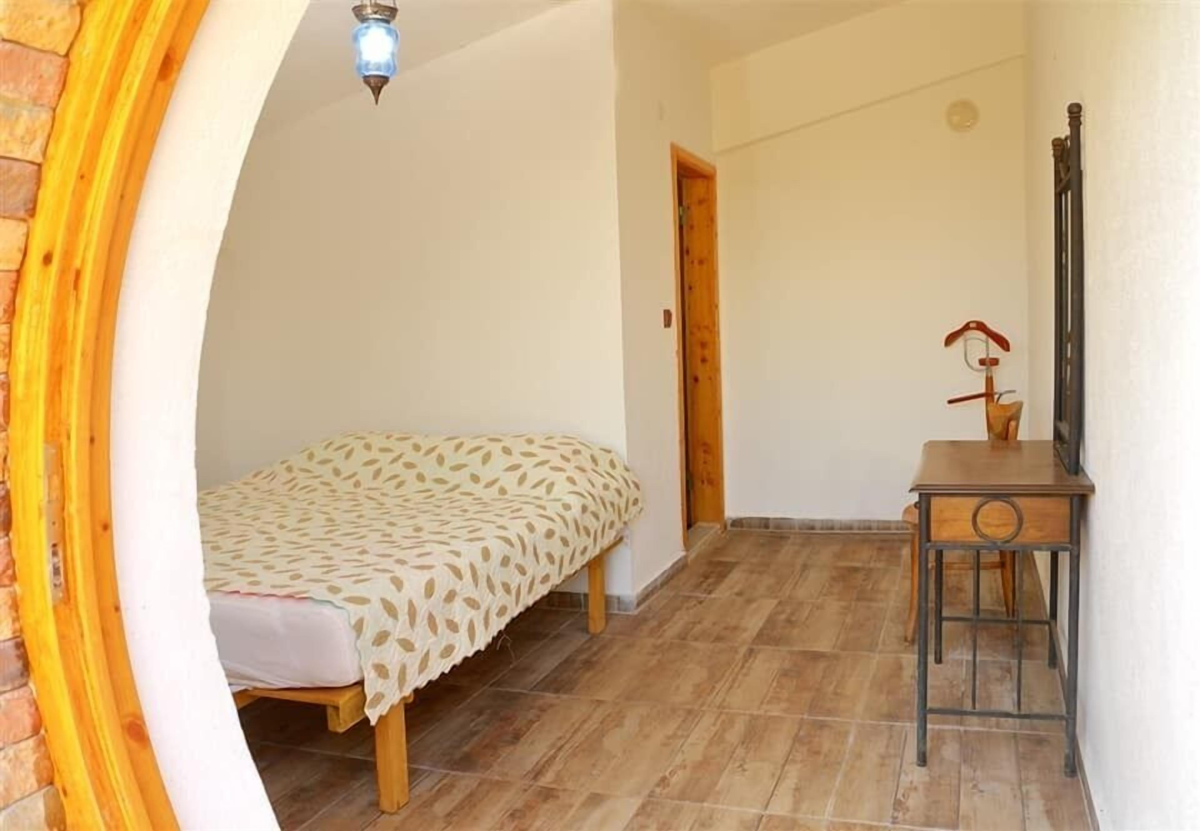 Una habitación pequeña con una cama, un escritorio y una puerta.