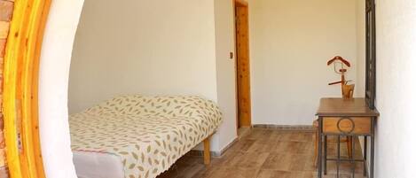 A small room with a bed, a desk, and a door.