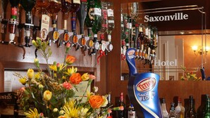 Uma área de bar com várias garrafas de bebidas e uma placa indicando 'Saxonville Hotel'.