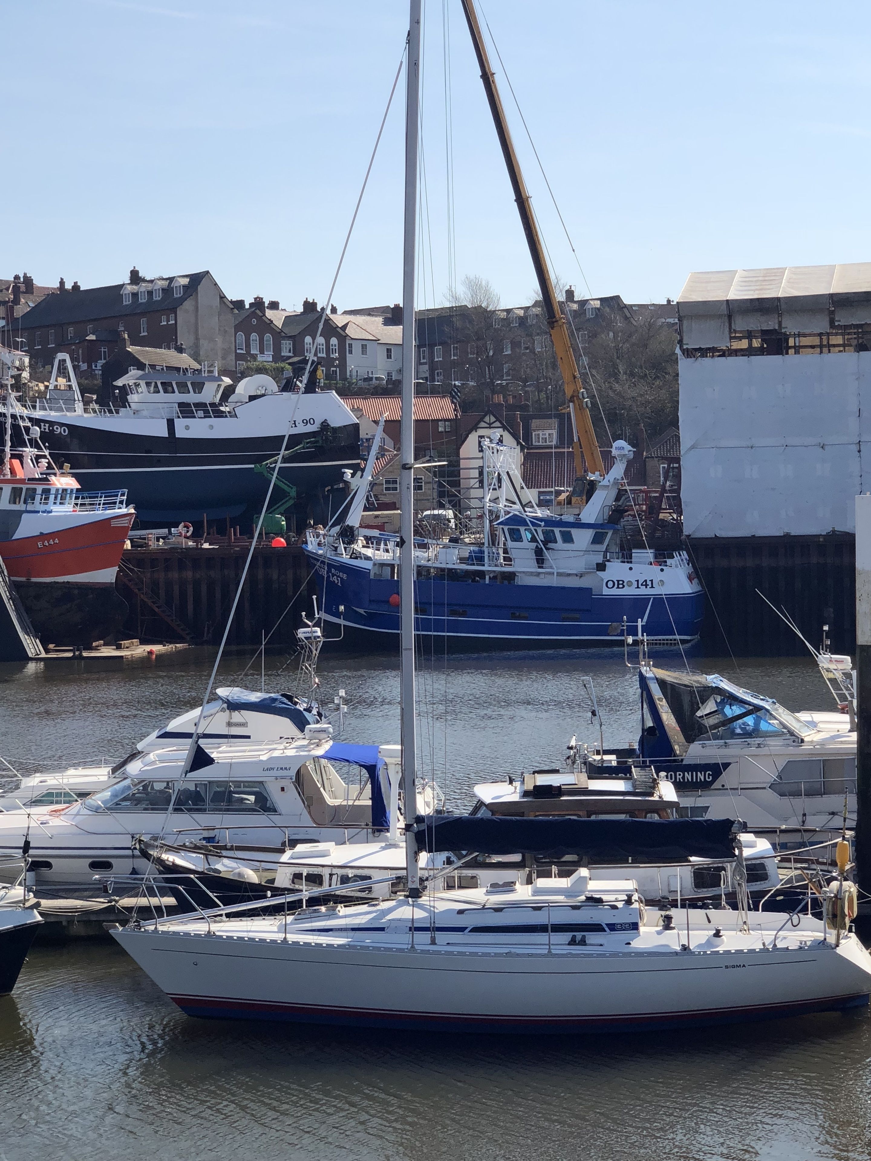 A marina with various boats docked, including a prominent white yacht named SIGMA.