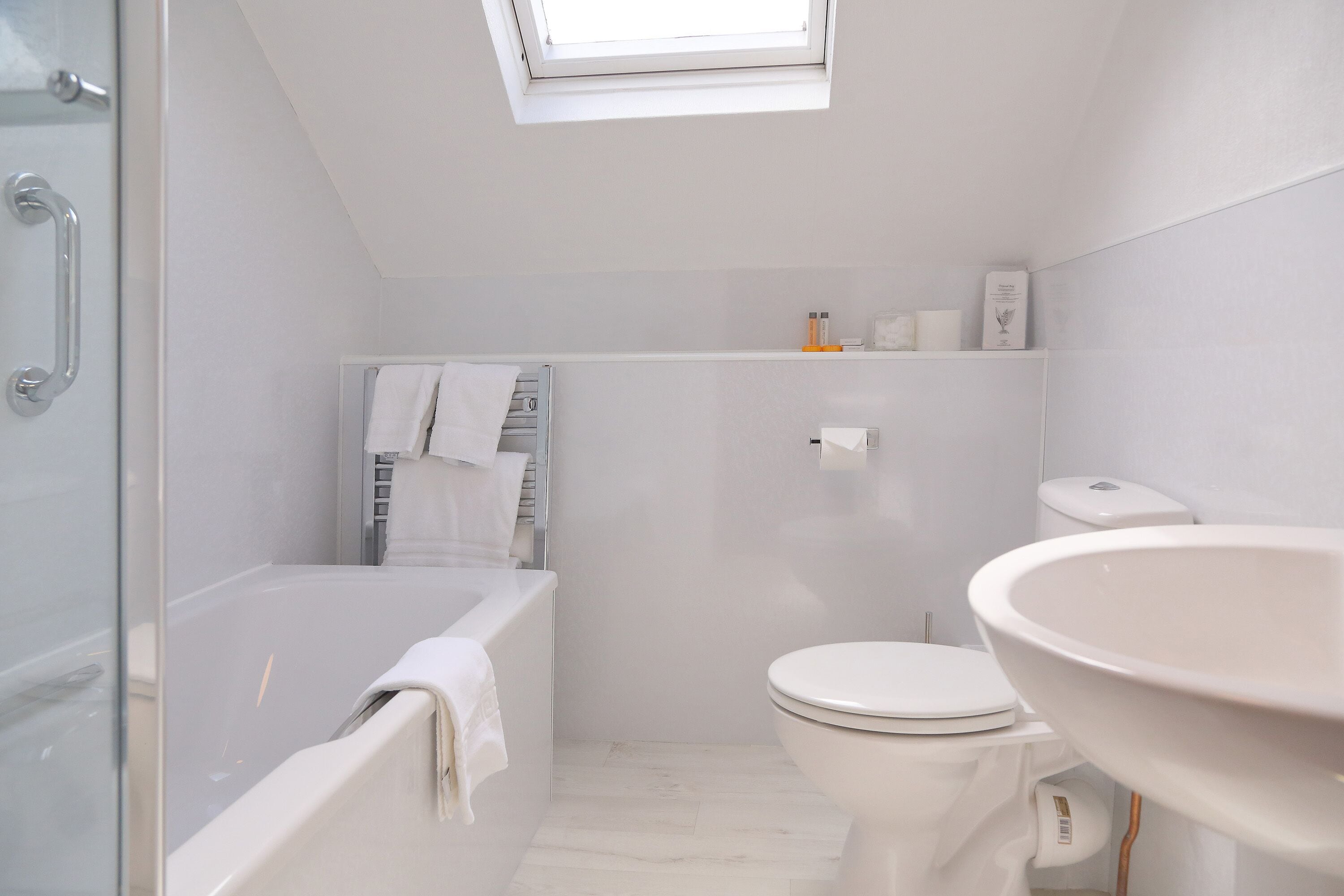 A modern bathroom with a glass shower enclosure, a bathtub, a toilet, and a large sink.