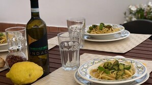 Une table à manger dressée avec des assiettes remplies de nourriture, des verres et une bouteille de vin, le tout se détachant sur un ciel dégagé et des montagnes lointaines.