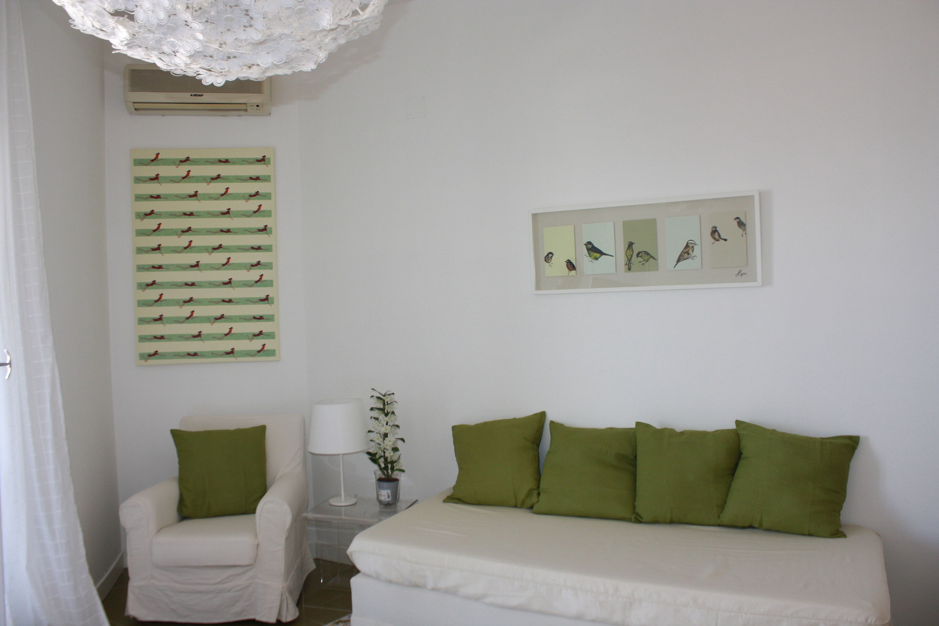 Un dormitorio con una cama, una silla y una pared decorada con ilustraciones de pájaros.
