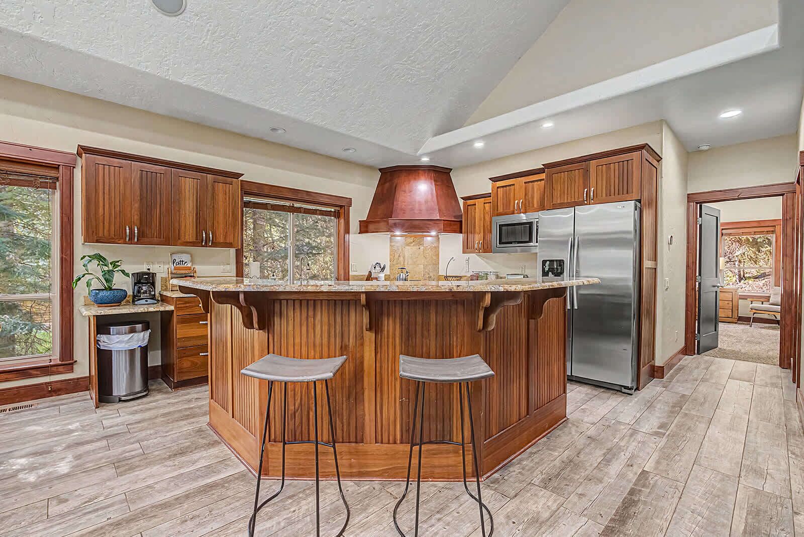 Una cocina con armarios de madera, un refrigerador de acero inoxidable, un microondas y una isla grande con taburetes de bar.