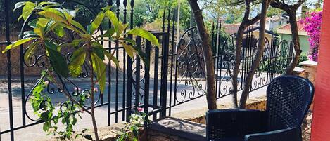 A patio with wicker chairs, a stone wall, and a metal fence.