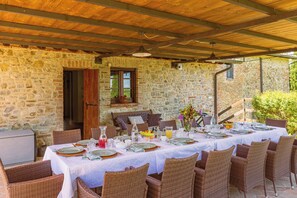 A stone-walled outdoor dining area with a covered roof, wicker chairs, and a table set for a meal. - UMBRIA ESTATE 2 VILLAS, 2 HEATED POOLS , 2 JACUZZI  TOWN WALKING DISTANCE (città della pieve)