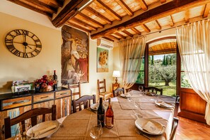 A dining area with a wooden ceiling, a clock, a table set for two, and a view of the outdoors.