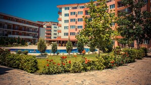 A multi-story hotel with a swimming pool surrounded by landscaped gardens and a clear blue sky. - MENADA * Privilege Fort Beach * Cosy studio  (Elenite)