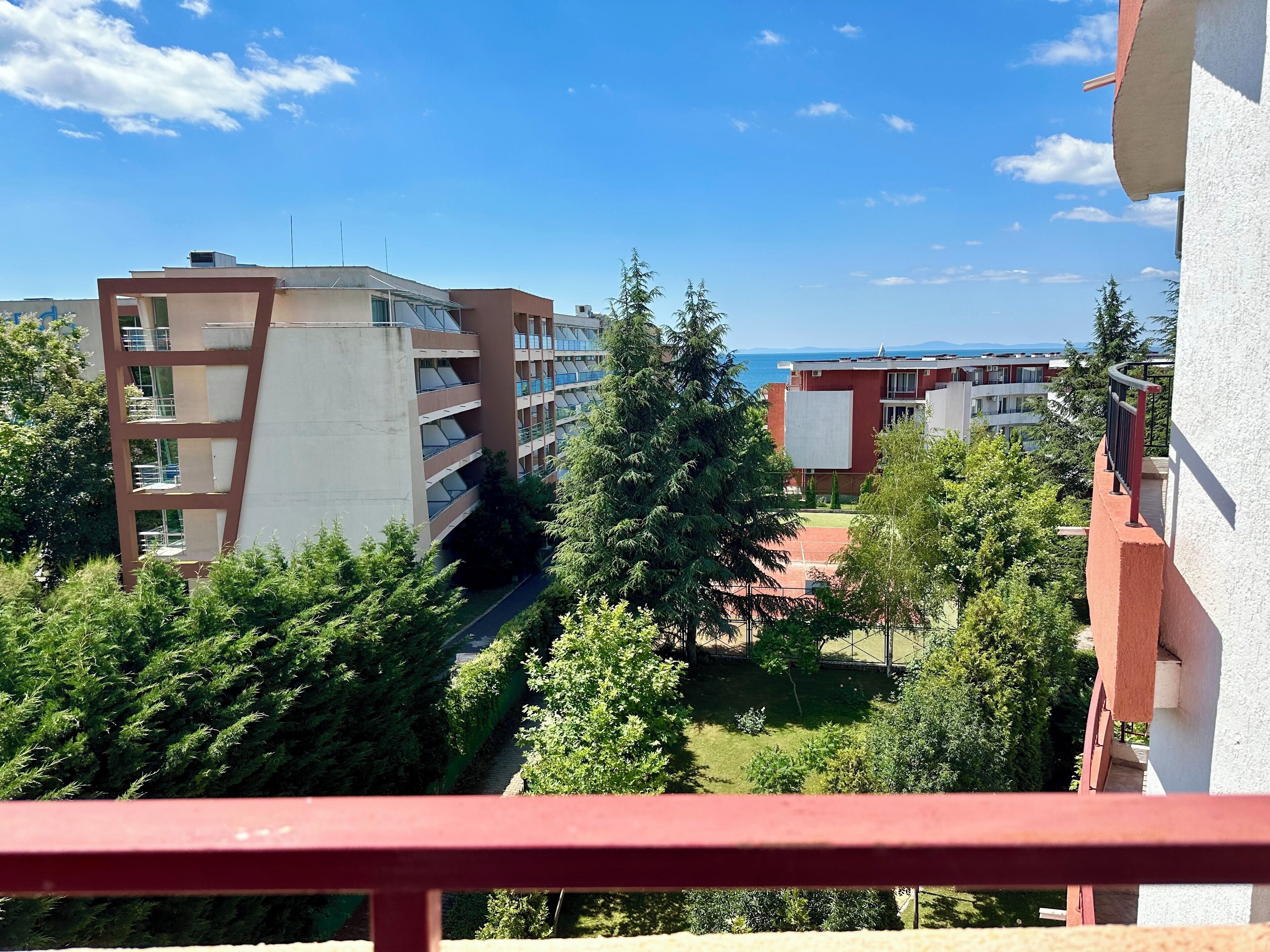 A residential building with multiple floors, a balcony, and a view of the sea.