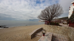 A beach with a stone pathway leading to a red fence.