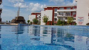 A swimming pool with a tiled deck, surrounded by buildings with balconies and air conditioning units. - MENADA * Privilege Fort Beach * Cosy studio  (Elenite)