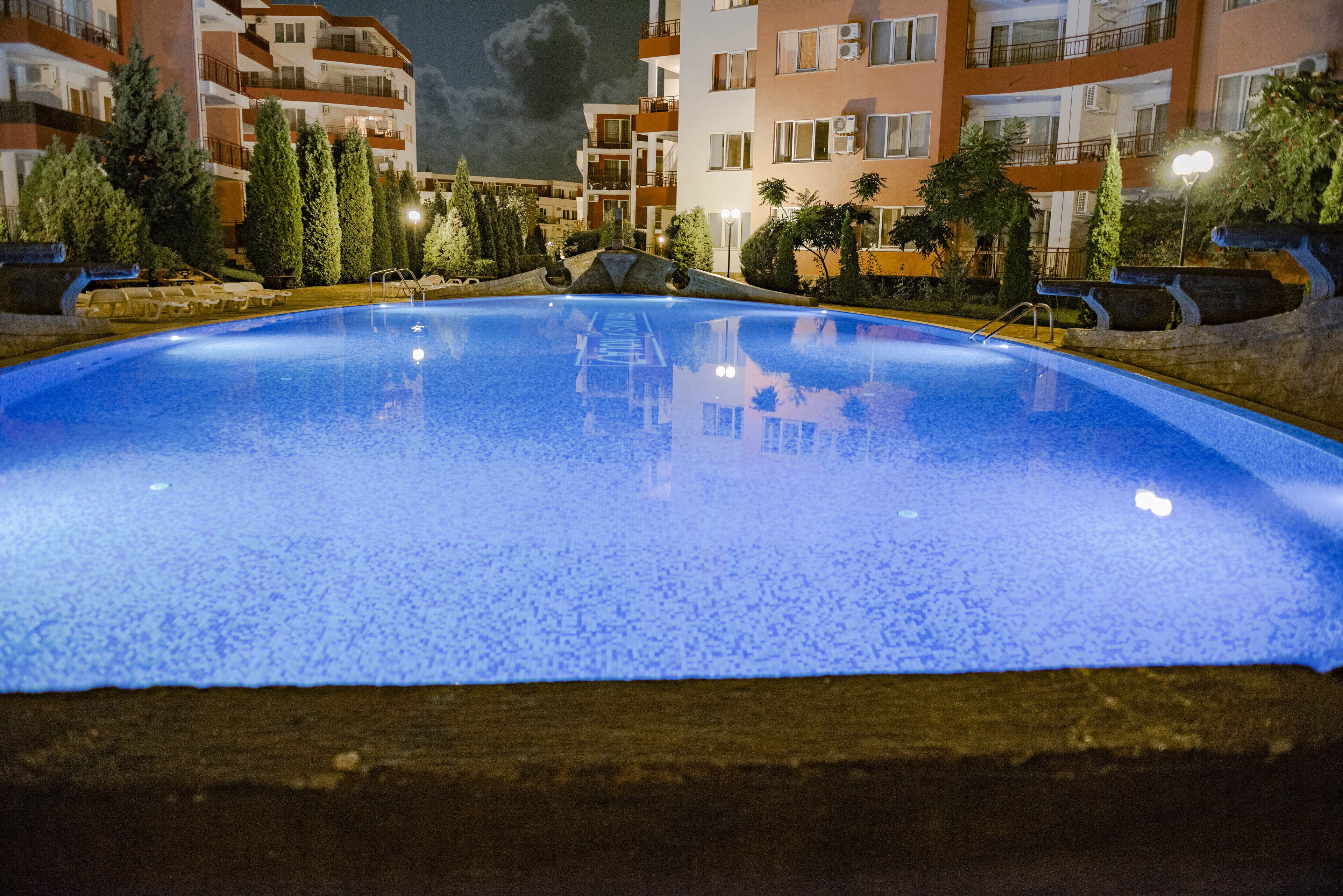 A swimming pool surrounded by apartment buildings at night.