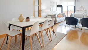 Un salon moderne avec un coin repas, comprenant une table blanche, des chaises, un canapé et une lampe.