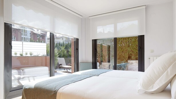 Une chambre moderne avec un grand lit, une vue sur le patio extérieur et une porte-fenêtre coulissante donnant sur le balcon.