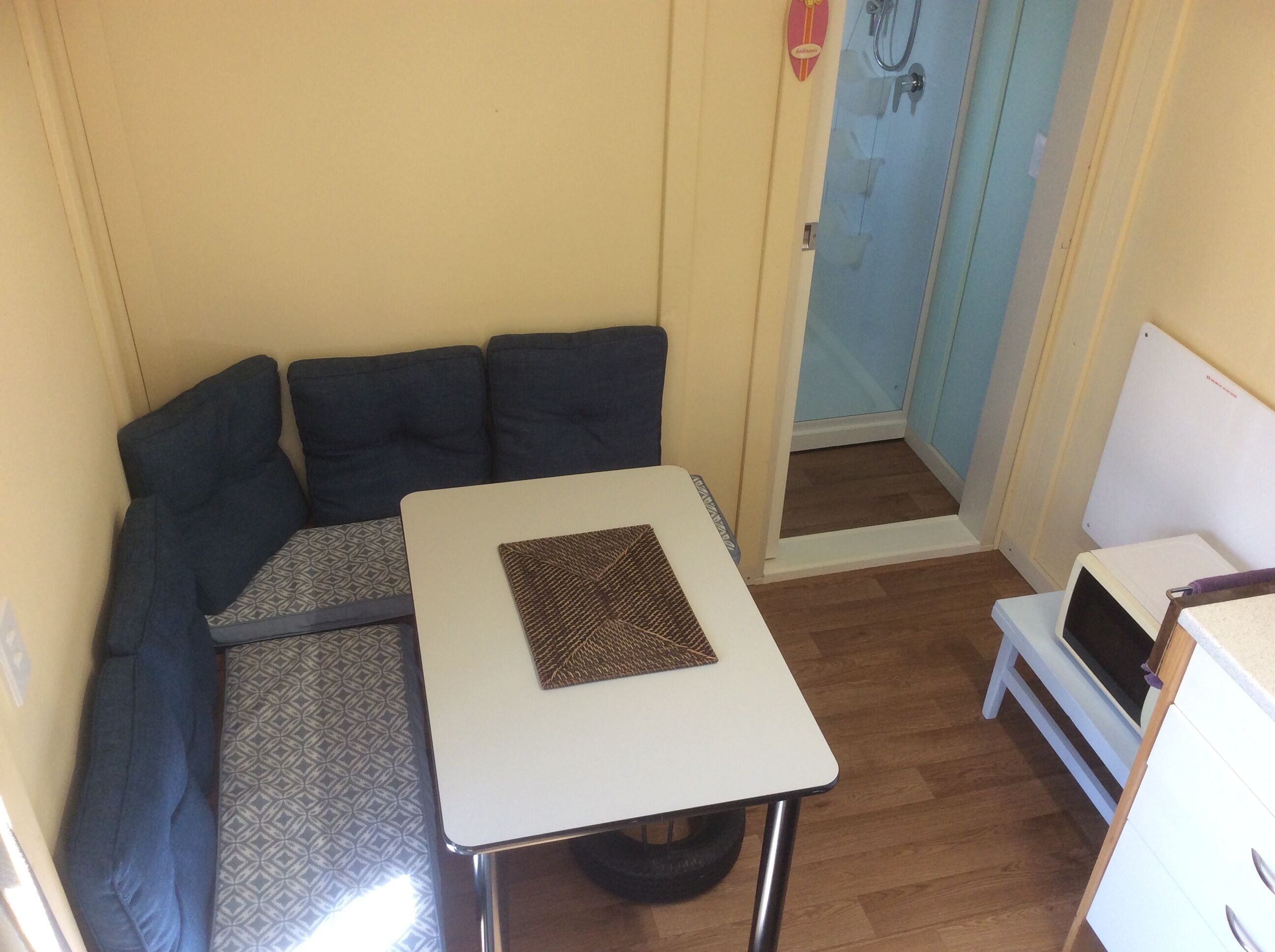 Ein gemütlicher Raum mit einem kleinen weißen Tisch, einem gemusterten Teppich, einer Couch und einer Tür zum Badezimmer.