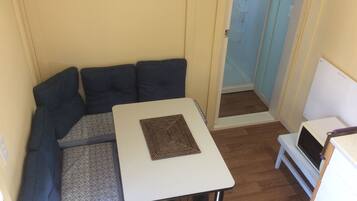 Ein gemütlicher Raum mit einem kleinen weißen Tisch, einem gemusterten Teppich, einer Couch und einer Tür zum Badezimmer.