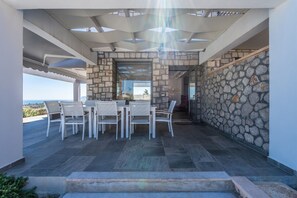 An outdoor patio area with a stone wall, a table with chairs, and a view of the landscape.