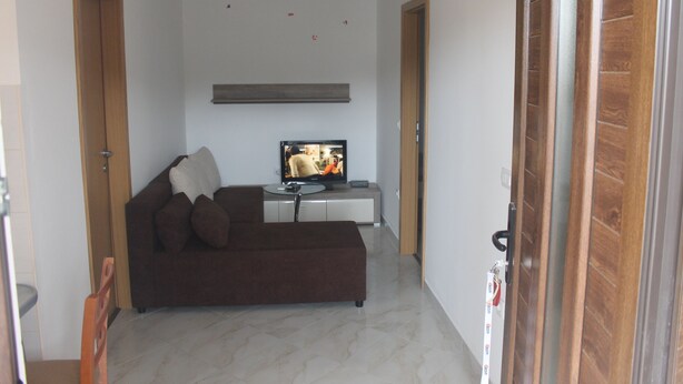 A modern living room with a brown sofa, a flat-screen TV, and a small coffee table. - Apartman Gracijela Poreč (Parenzo)
