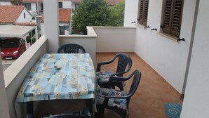 A balcony with a table and chairs, a red car parked outside, and a tree in the background. - Apartman Gracijela Poreč (Parenzo)