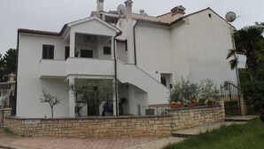 A two-story building with a stone foundation, a satellite dish, and a private parking sign. - Apartman Gracijela Poreč (Parenzo)
