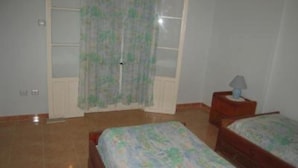 Un dormitorio con dos camas, una mesita de noche, una ventana con cortina y una puerta.