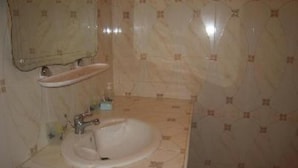 Un baño con lavamanos, espejo y paredes con azulejos.