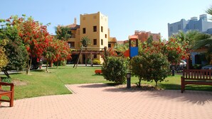 Un patio con un sendero empedrado, bancos y un edificio con fachada amarilla.