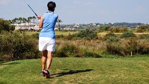 Una persona jugando al golf en un día soleado.