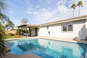 A swimming pool with a covered patio area, a barbecue grill, and palm trees. - Gilbert Oasis | Pool, Putting Green, Sleeps 10 (Gilbert)