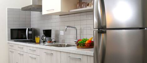 A modern kitchen with a stainless steel refrigerator, a microwave, and a coffee maker.