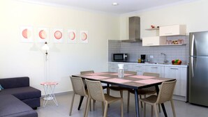 A modern kitchen with white cabinets, a stainless steel refrigerator, and a dining area with a table and chairs. - Casa Alessandra 2bdr (Oranjestad-West)