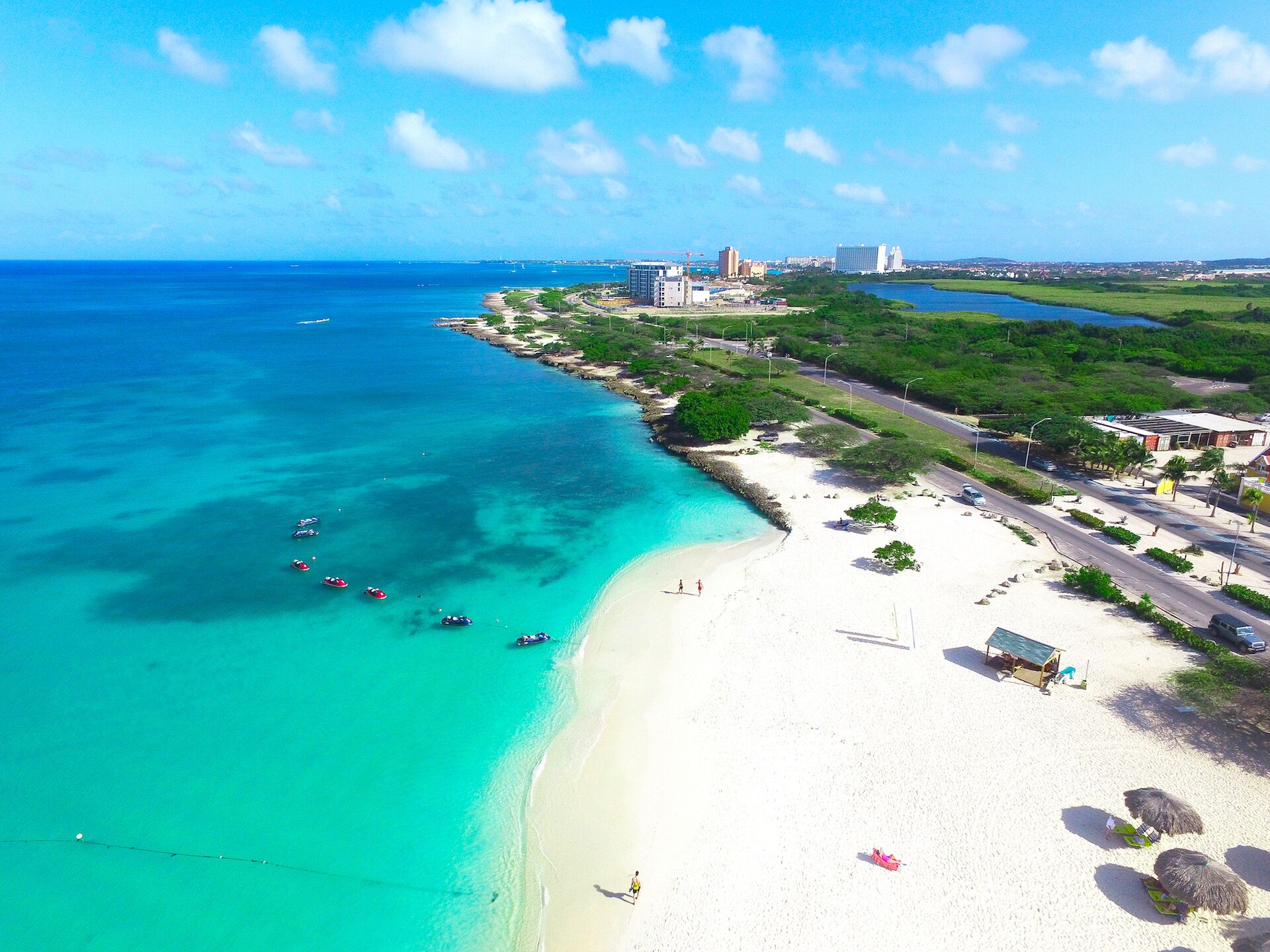 Een kuststrand met helder turquoise water, een zandstrand en enkele boten.
