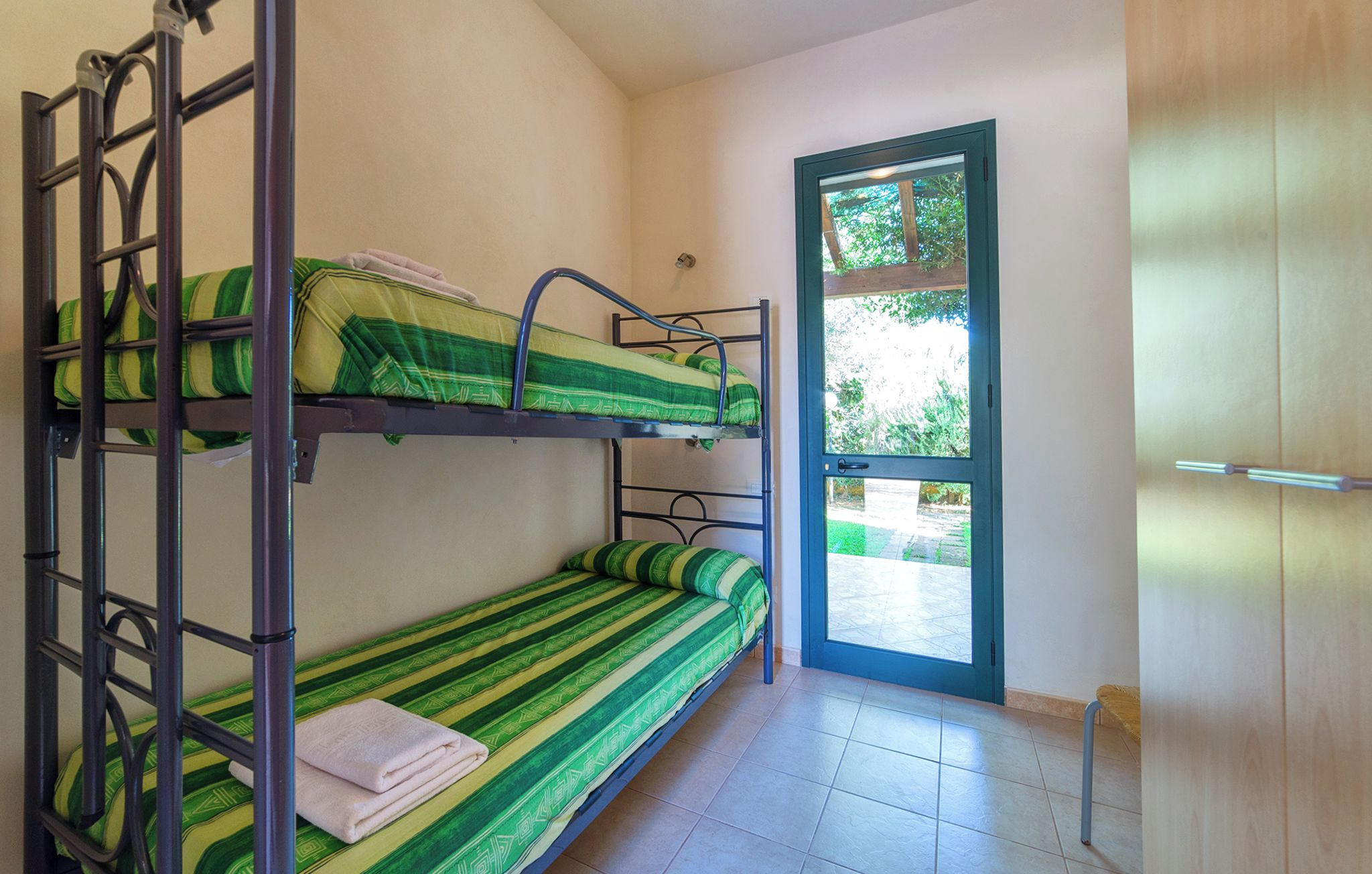 Une chambre de dortoir avec des lits superposés, une fenêtre et une porte.