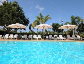 Une piscine avec des chaises longues et des parasols.