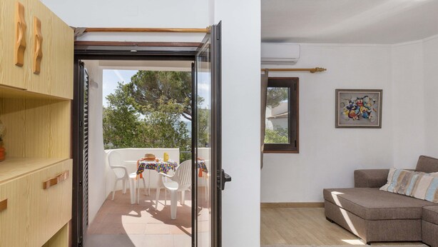 A modern living room with a sectional sofa, a dining area with a table and chairs, and a sliding glass door leading to an outdoor patio. - Apartment Maresia, 50 metres from the Oura Beach and 2 minutes from the Strip (Albufeira)