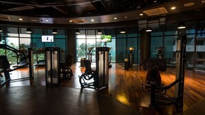 A gym with exercise equipment, large windows, and a TV screen. - Azure Tropical Paradise in your Backyard (Parañaque)