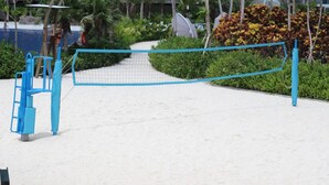 A beach volleyball net with blue poles, surrounded by a sandy area and greenery. - Azure Tropical Paradise in your Backyard (Parañaque)